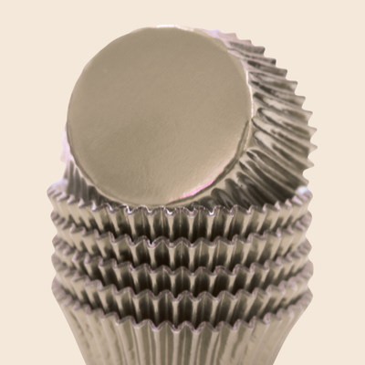 Metallic cupcake liner on a beige background. Foil cupcake wrappers with shiny surfaces for baking.